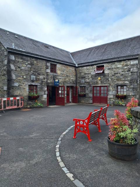 Stone building with red benches and flowers.