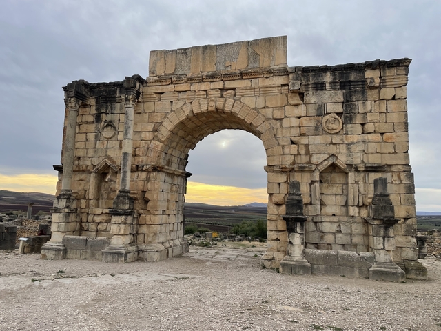Ancient stone archway with sunset in the background.
