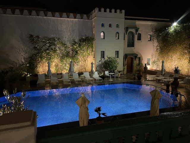 Illuminated pool area at night with lounge chairs