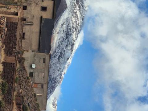 A snow-capped mountain with a building in the foreground.