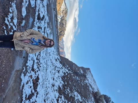       A woman standing on snowy ground with mountains in the background.
  