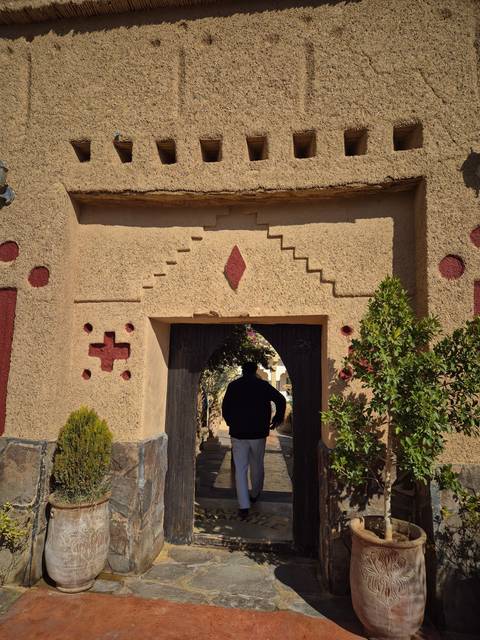       A person walking through an archway in a traditional adobe building.
  