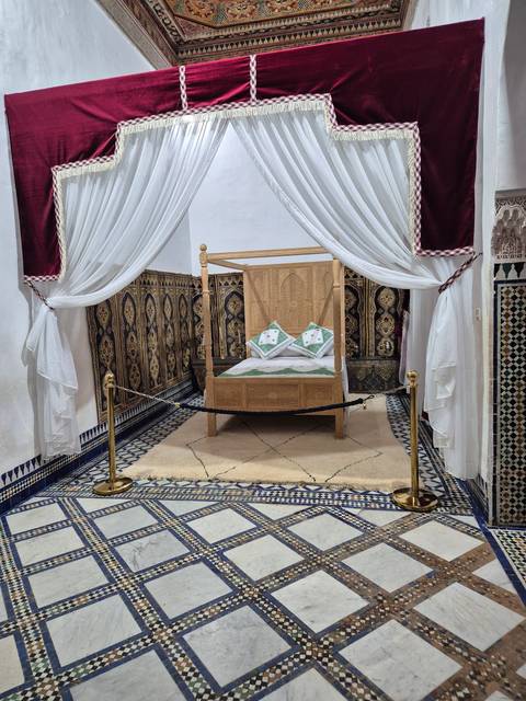       Interior of a traditional room with vibrant carpets and a wooden cradle.
  