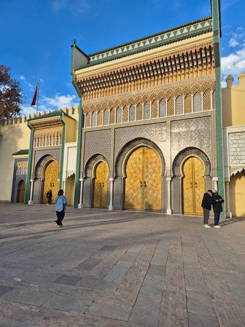      Impressive golden doors and mosaic architecture in a vast courtyard.
  