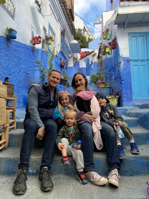      Family sitting together on steps in a blue-painted alleyway.
  