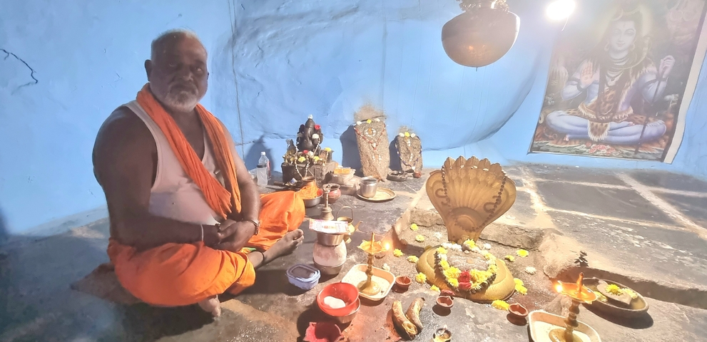      Man sitting with religious items in a blue room.
  