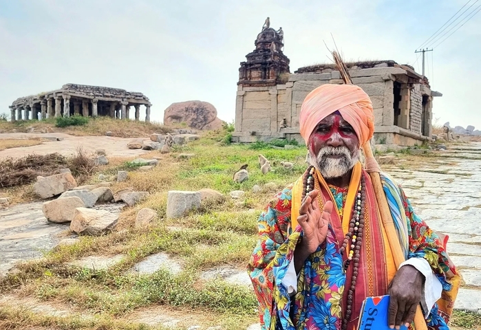       Man dressed in traditional attire near ancient ruins.
  