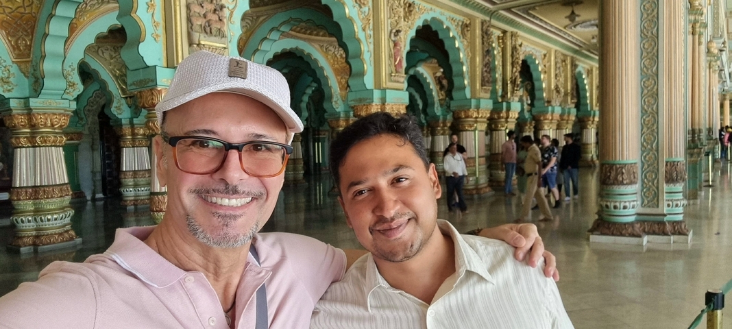       Two men taking a selfie inside an ornately decorated hall.
  