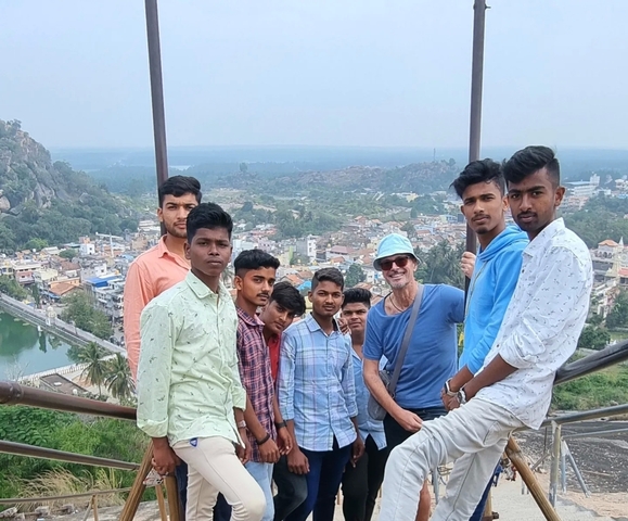       Group of people posing on a viewpoint overlooking a town.
  