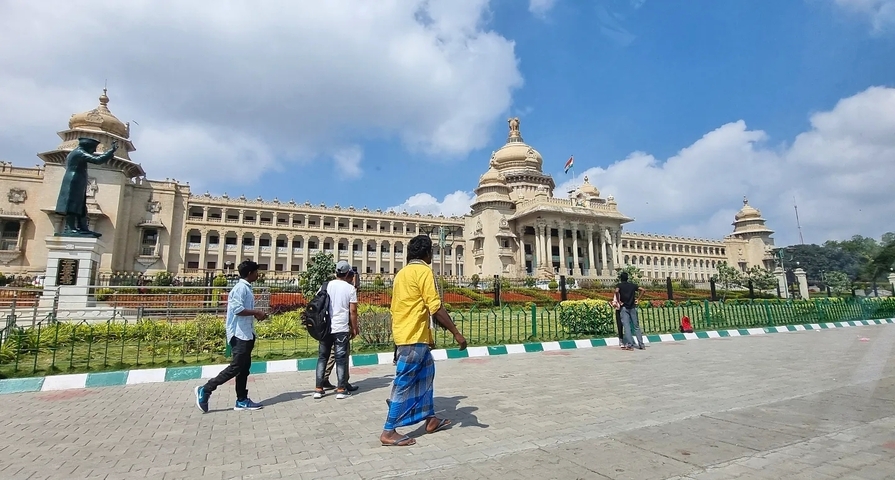       Street view of a grand government building with people and a statue.
  