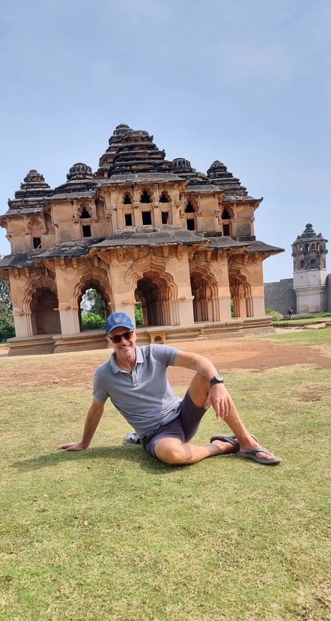       Man sitting in front of a historic temple structure.
  
