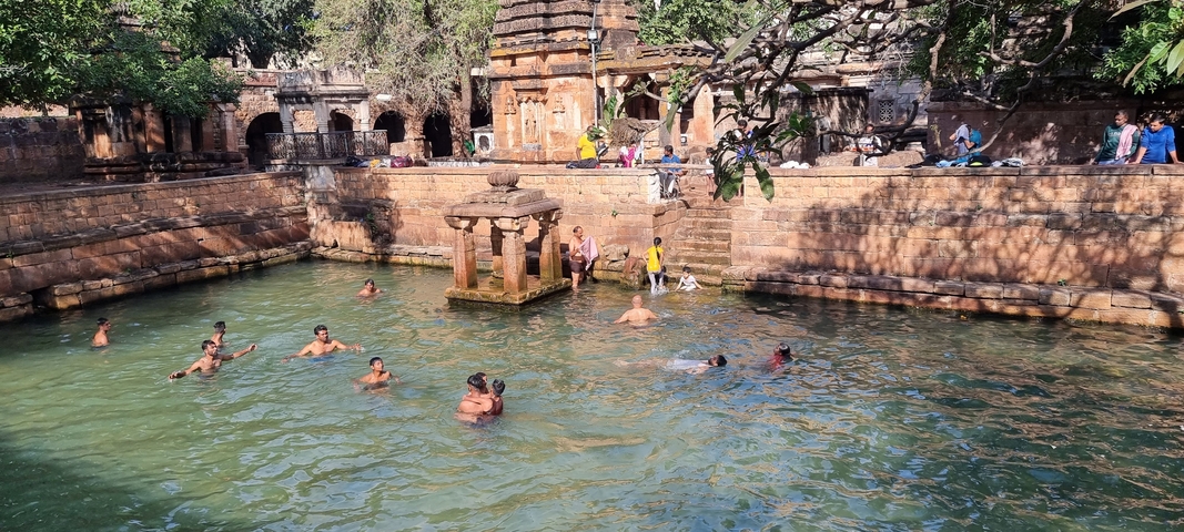       People swimming and relaxing in a historic water tank.
  