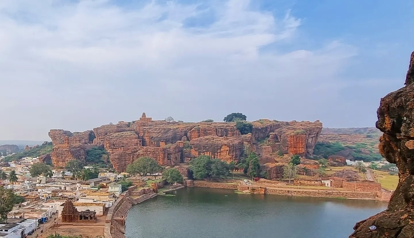       Large rock formation by a lake with a small town below.
  