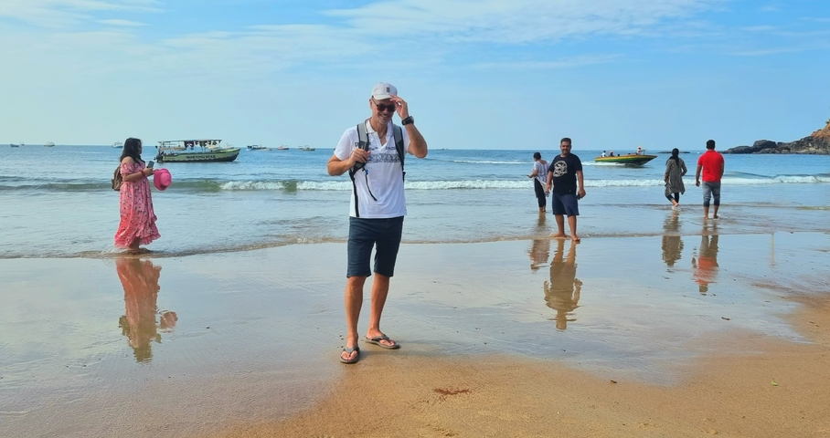       People enjoying the beach with boats in the water.
  