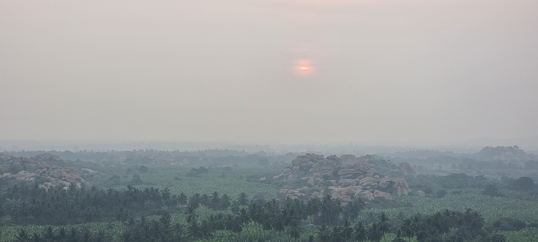       Sunset over a landscape with distant rocky hills.
  