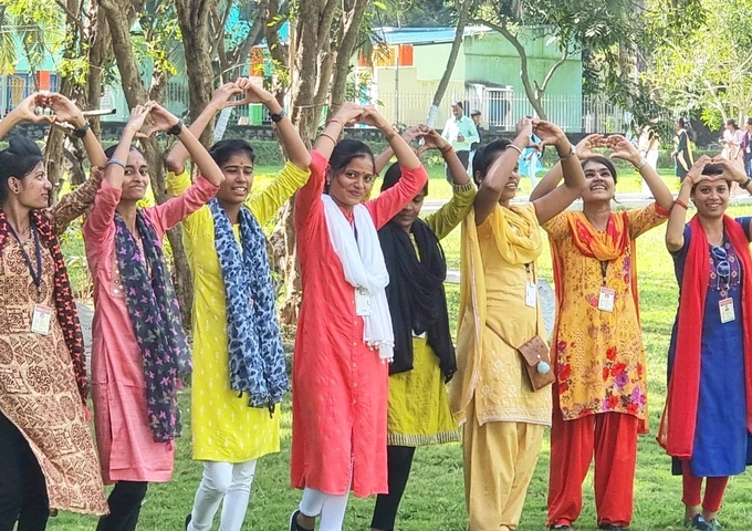       Group of women standing in a line making a heart shape with their arms.
  