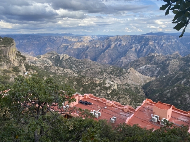 Wide view of a canyon with a building on the edge.