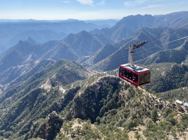 Cable car traveling over a rugged mountain landscape.