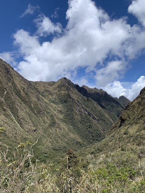       Mountain range with scattered clouds in blue sky.
  