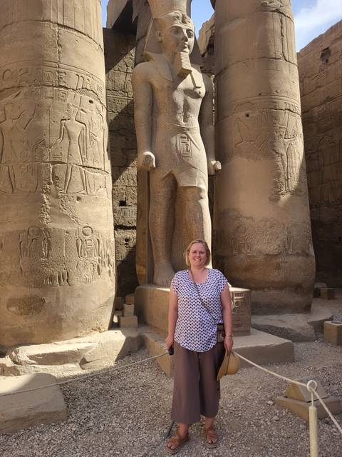 Woman standing in front of an ancient statue.