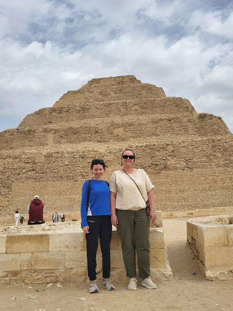 Two people standing in front of a stepped pyramid.