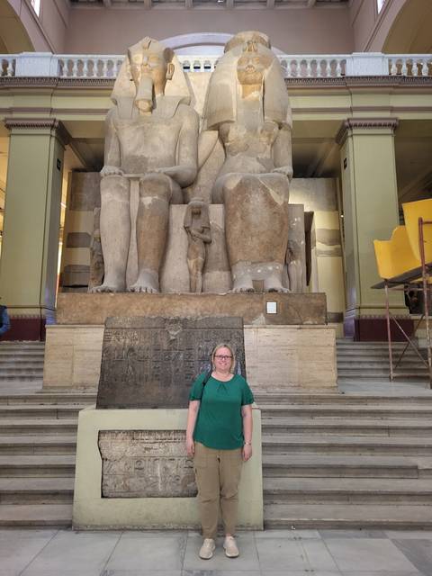 Woman standing in front of ancient statues inside a building.