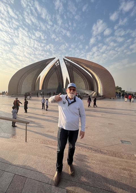       A man posing with a thumbs up in front of a monument.
  