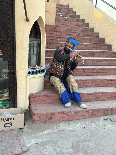       A person playing a flute on steps with intricate design.
  