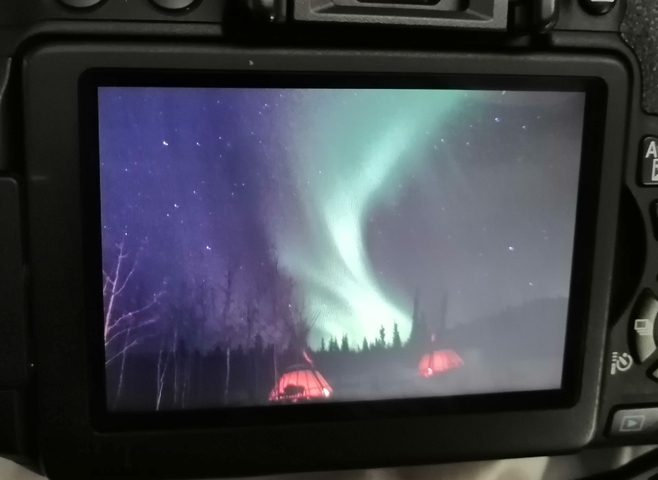       Northern lights captured on a camera screen in a dark setting.
  