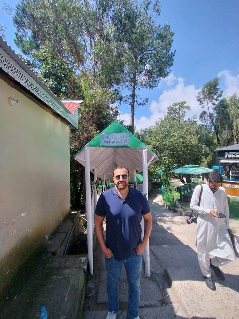 Person near a monument sign in a green setting.