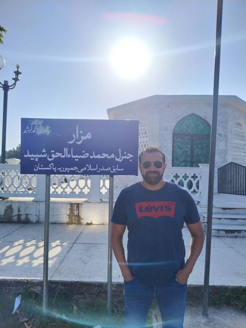 Person standing near a sign in a bright sunlight.