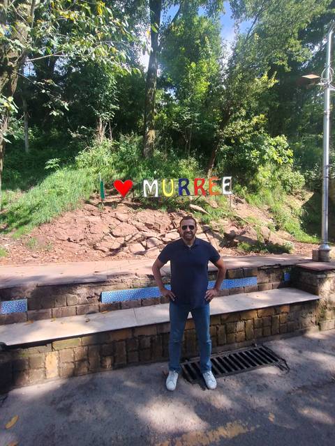 Person posing with a greeting sign for Murree.