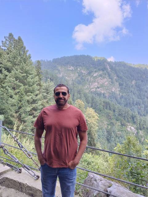       Person posing against a scenic mountain backdrop.
  