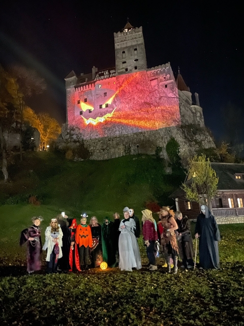 Group in costume posing at night in front of a lit-up building.