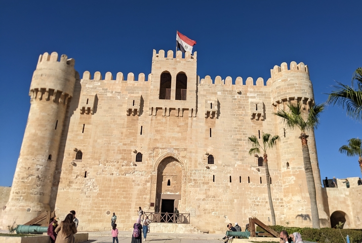 Fortress with a national flag and crenelated towers.
