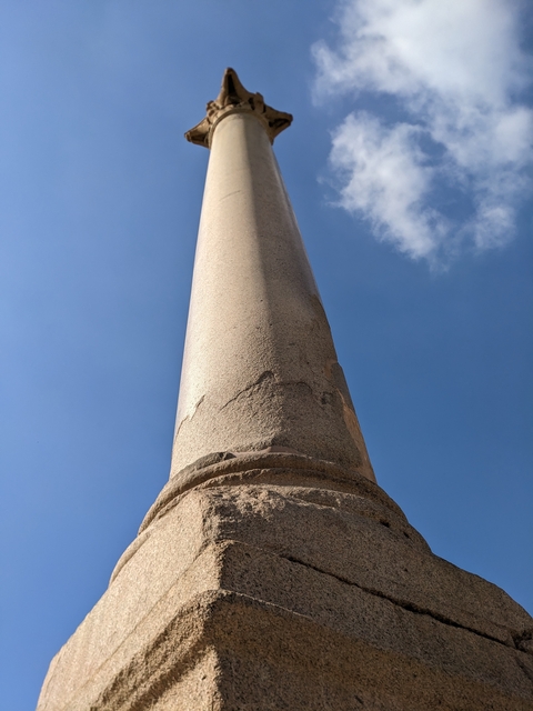 Tall stone column reaching into a clear blue sky.