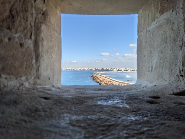 Seaside view between two stone walls framing the distant shore.