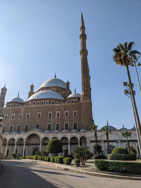 Mosque with multiple domes and tall minarets against a clear sky.