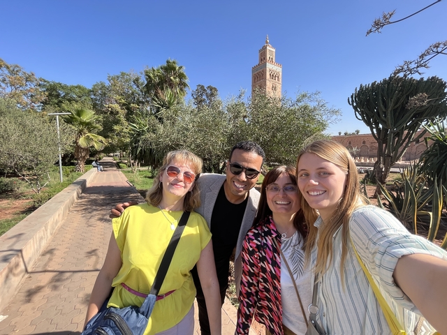       Group photo in front of a tower and palm trees.
  