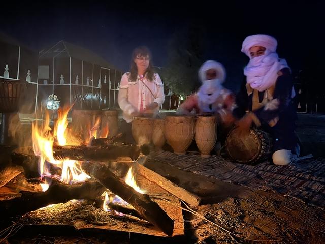       People playing drums around a fire during a night gathering.
  