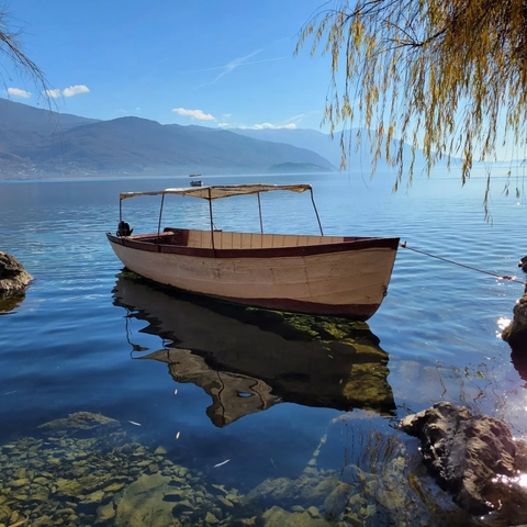       Old wooden boat docked at a serene lake.
  