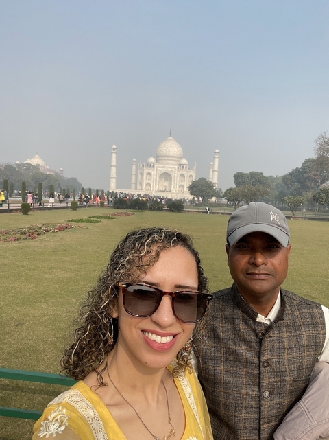       Two people posing with the Taj Mahal in the background.
  