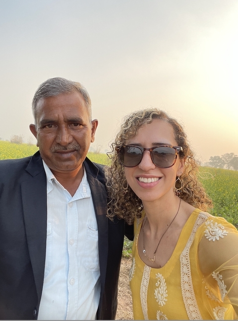       Two people smiling in a field during sunset.
  