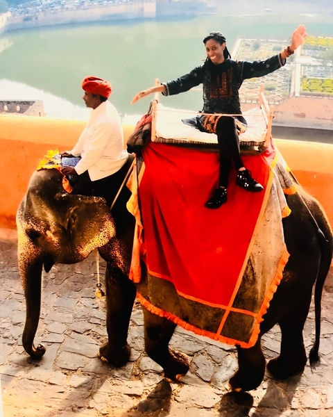 People riding on an elephant with vibrant blankets.