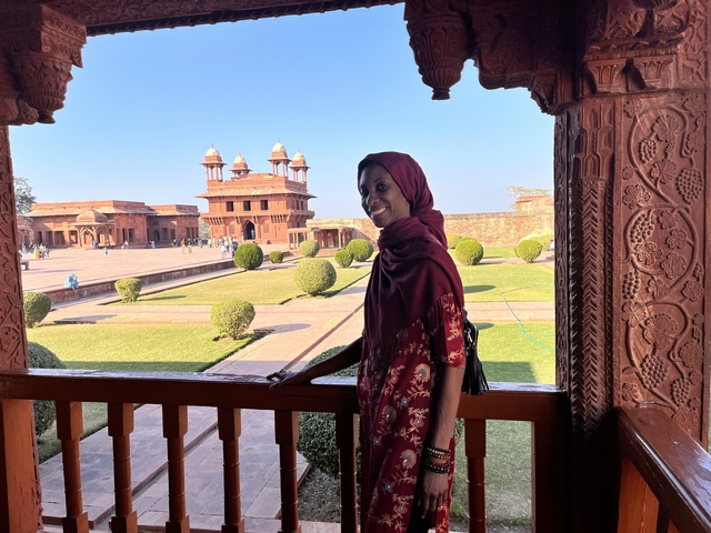 Woman in a red outfit at a historical complex.