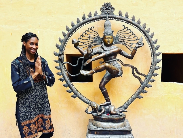 Woman standing next to a statue of Nataraja.