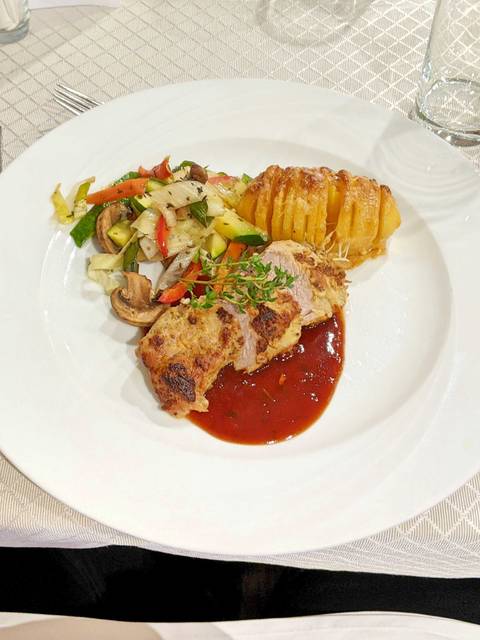 Plate with meat and potatoes accompanied by vegetables.