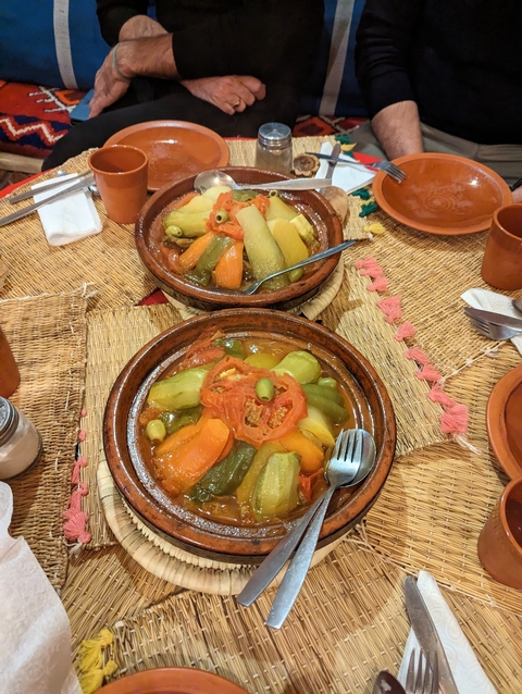       Colorful dishes of Moroccan tagine on a woven mat.
  