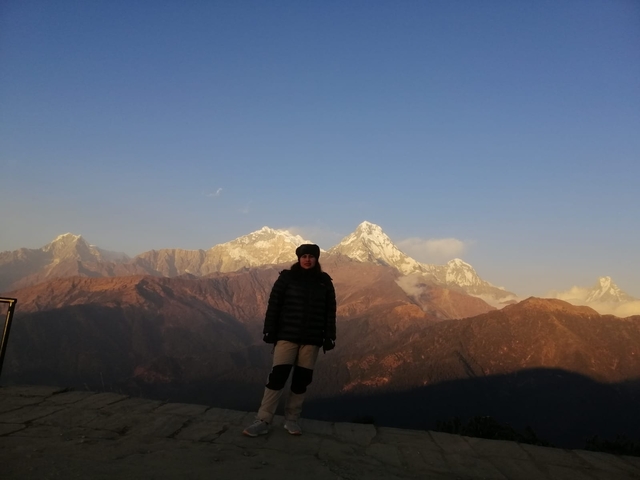 Person standing on a hill with a view of the Himalayas.