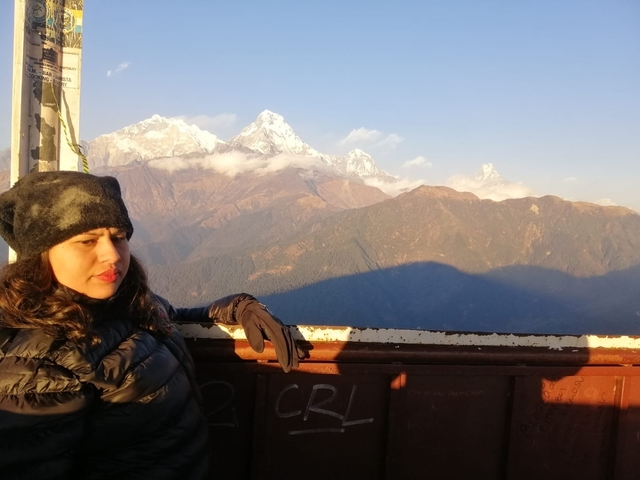 Person with mountain backdrop in cold weather gear.